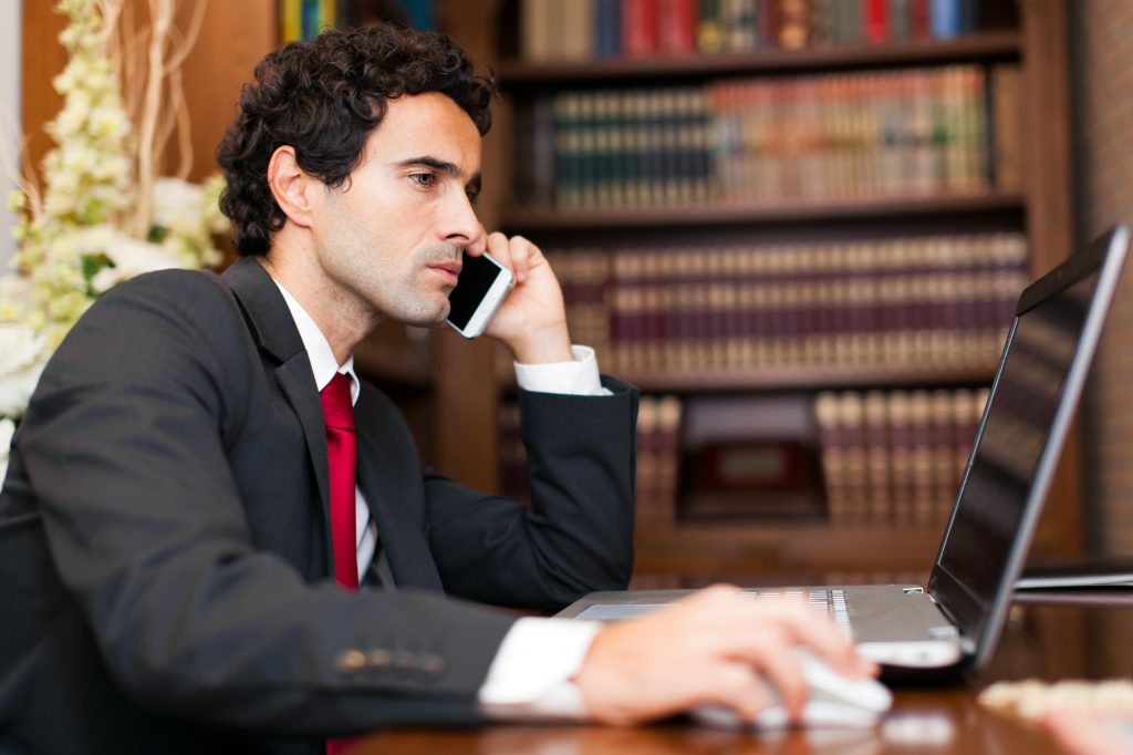 Lawyer in Front of a Laptop Making a Call in His office
