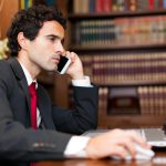 Lawyer in Front of a Laptop Making a Call in His office