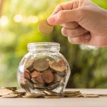 Person Dropping Coins on a Glass Jar