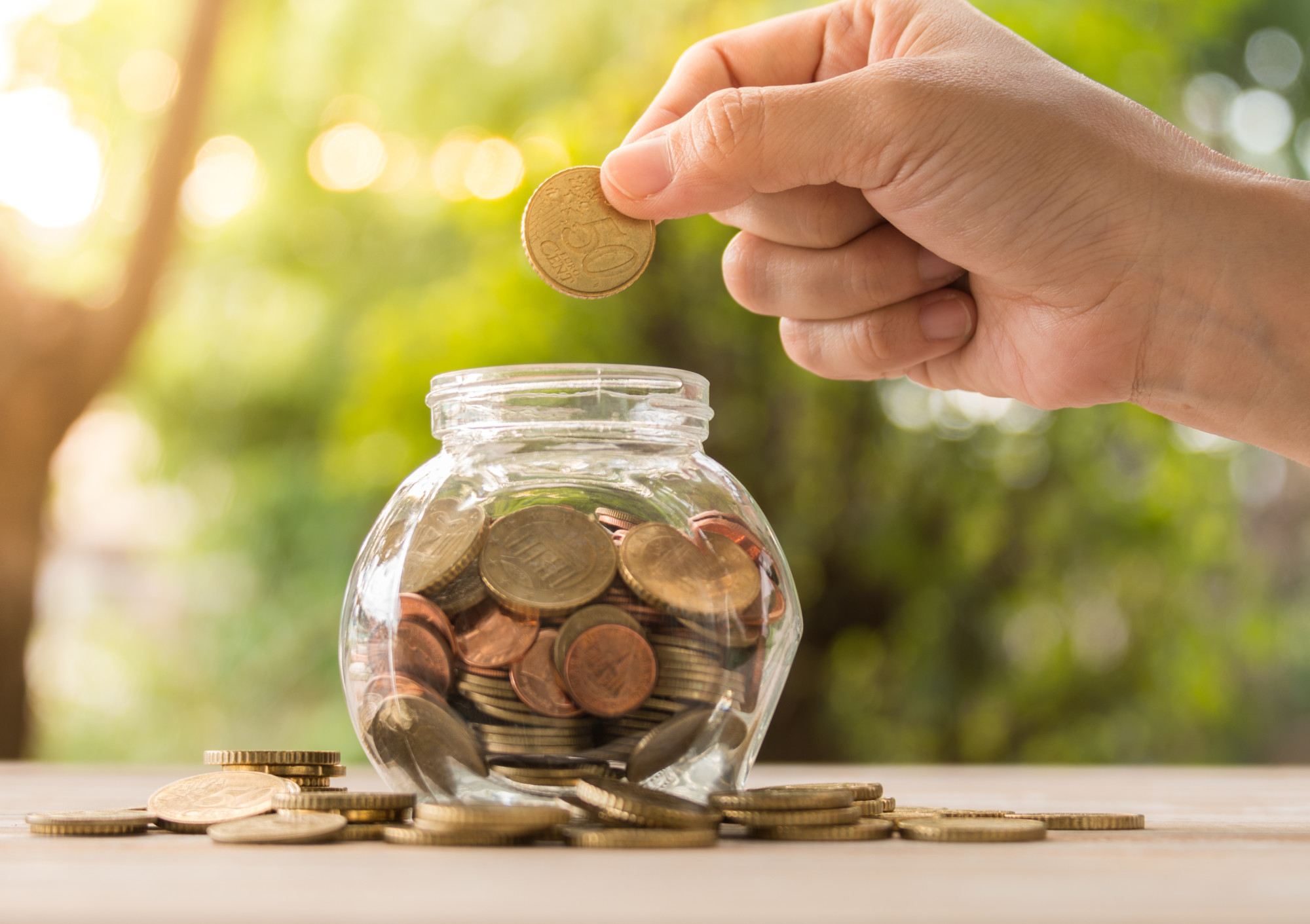 Person Dropping Coins on a Glass Jar